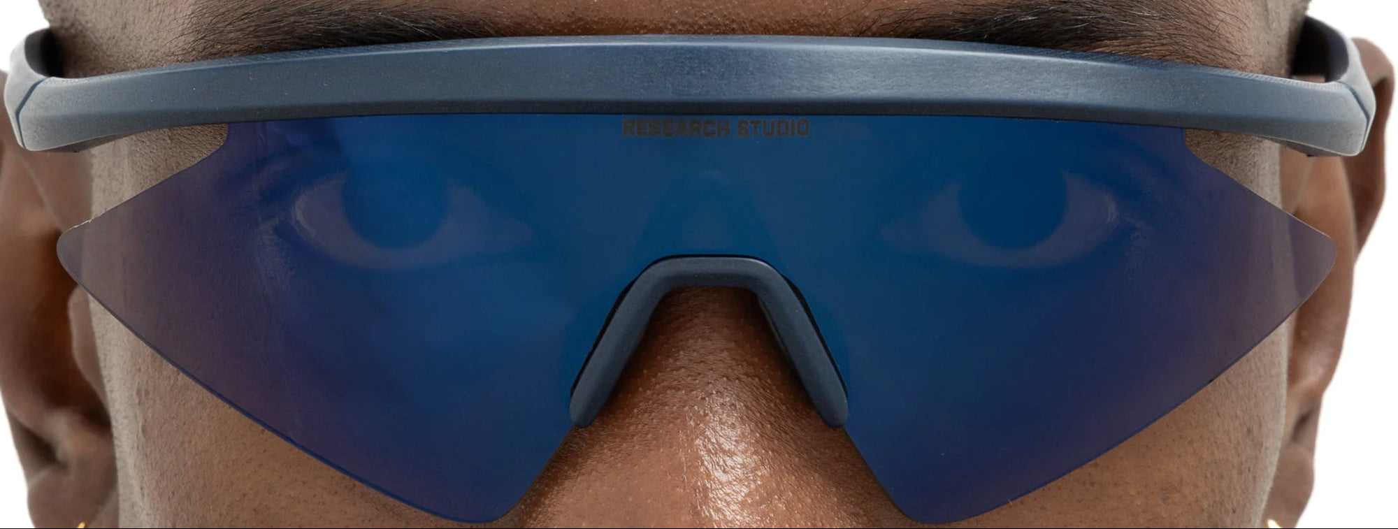 Close-up of a person wearing reflective blue sunglasses with a neutral background